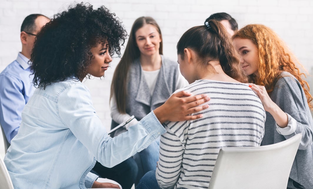 Addicted people comforting woman at psychotherapy session